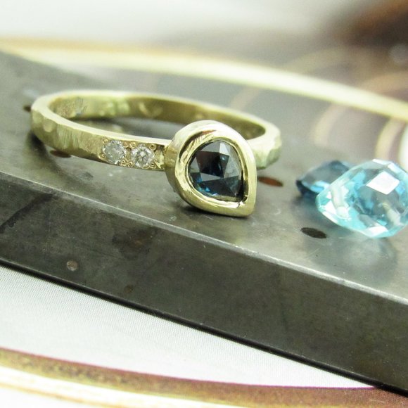 Engagement ring. 14K yellow gold ring set with a blue diamond and 2 diamonds.